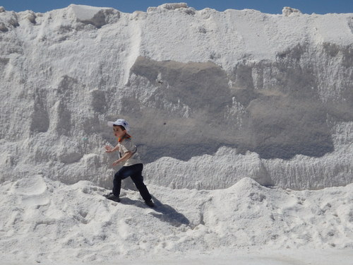 Kid playing next to a salt pile.